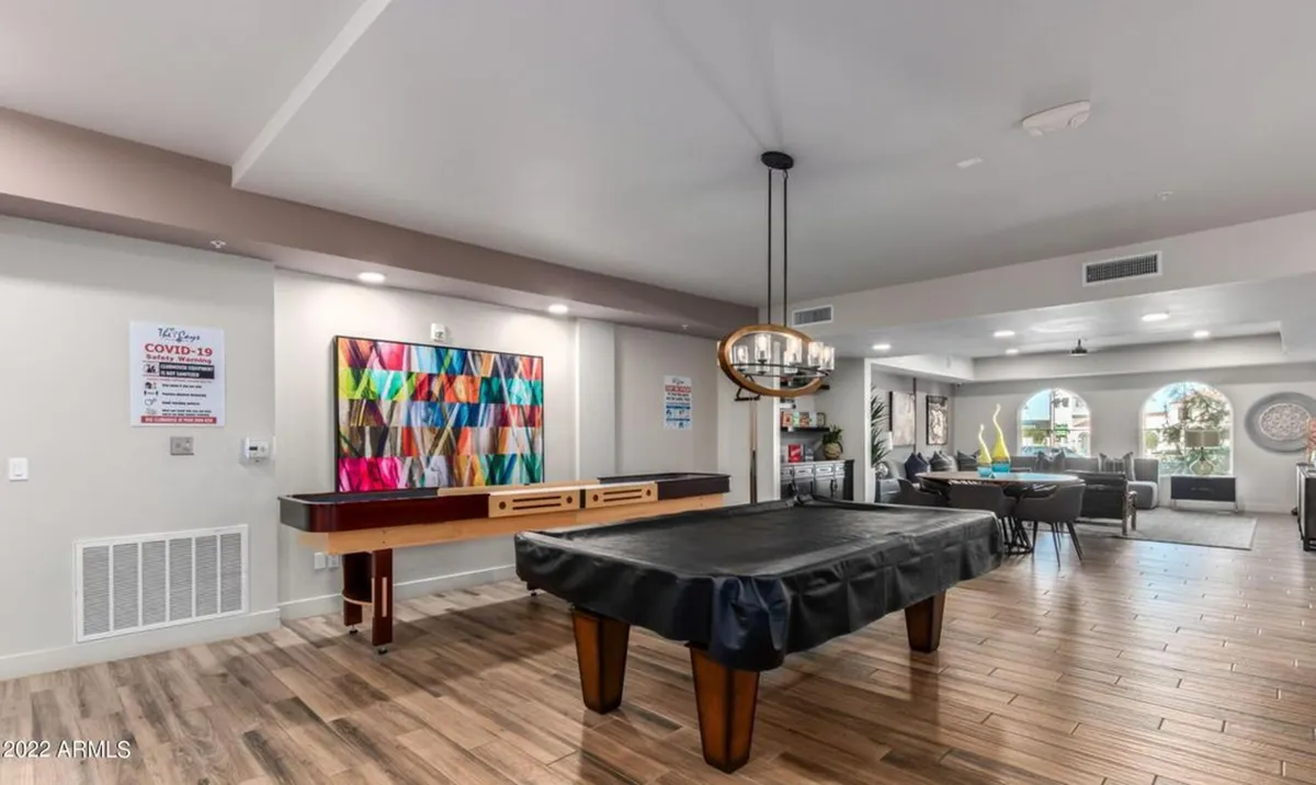 A cozy, stylish interior common area centered around a pool table with colorful wall art and a comfortable seating lounge. The space invites friendly games and social interaction.