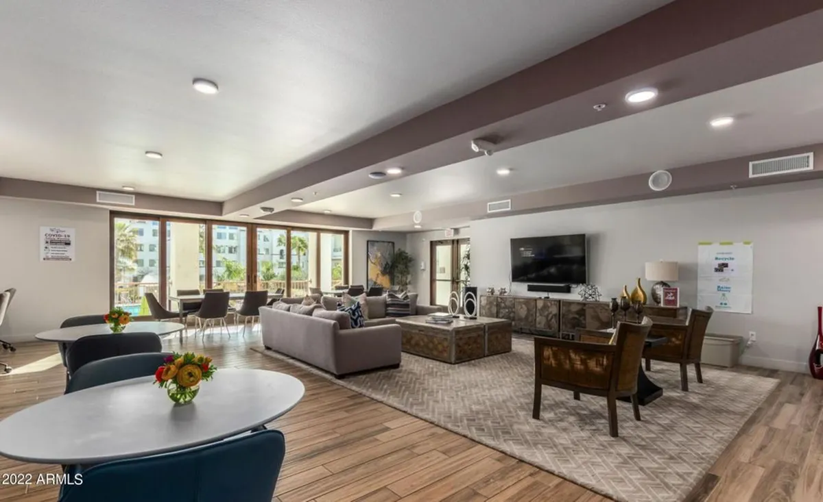 A spacious living room setup with comfortable sofa seating, large windows letting in natural light, and an entertainment center. The scene is ideal for social gatherings, relaxation, or watching TV, reinforcing a sense of community and comfort.