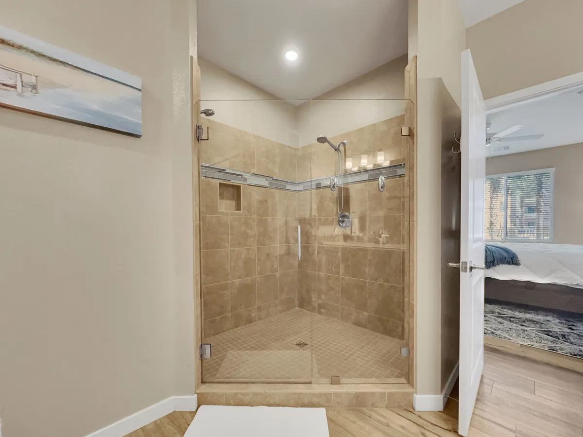 A contemporary bathroom featuring a glass shower enclosure, modern shower fixtures, neutral tile accents, and decorative wall art. The space is clean and calming, perfect for relaxing shower experiences.